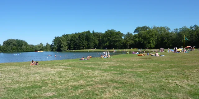 En plein été, des gens profitent du beau temps sur la plage et dans l'eau du lac de Bonnal - Vallée de l'Ognon