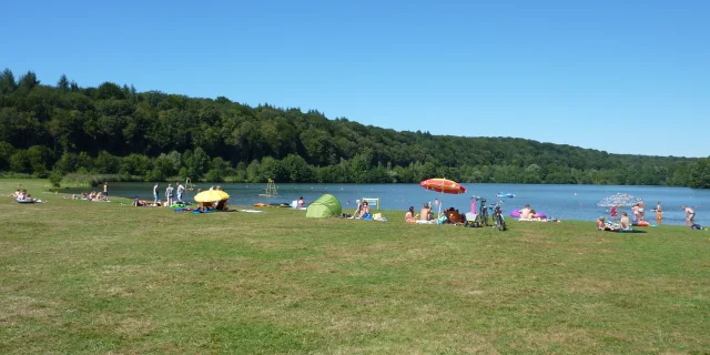 En plein été, des gens profitent du beau temps sur la plage et dans l'eau du lac de Bonnal - Vallée de l'Ognon