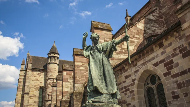 La statue en bronze de Saint Colomban érigée en 1947 accueille le visiteur devant la basilique Saint-Pierre de Luxeuil-les-Bains - Vosges du Sud